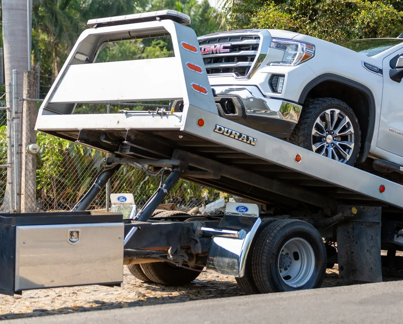 White pickup truck being loaded onto the tilted bed of a flatbed tow truck